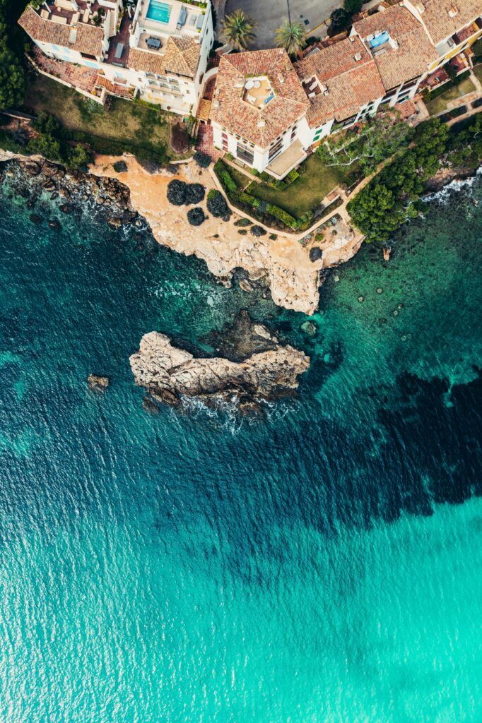 Stunning aerial shot of coastal houses and rocky shores in Palma, Spain, captured from above.